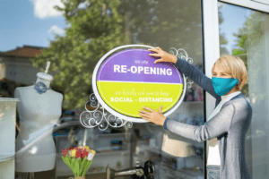 Woman placing a store re-opening sign on a store